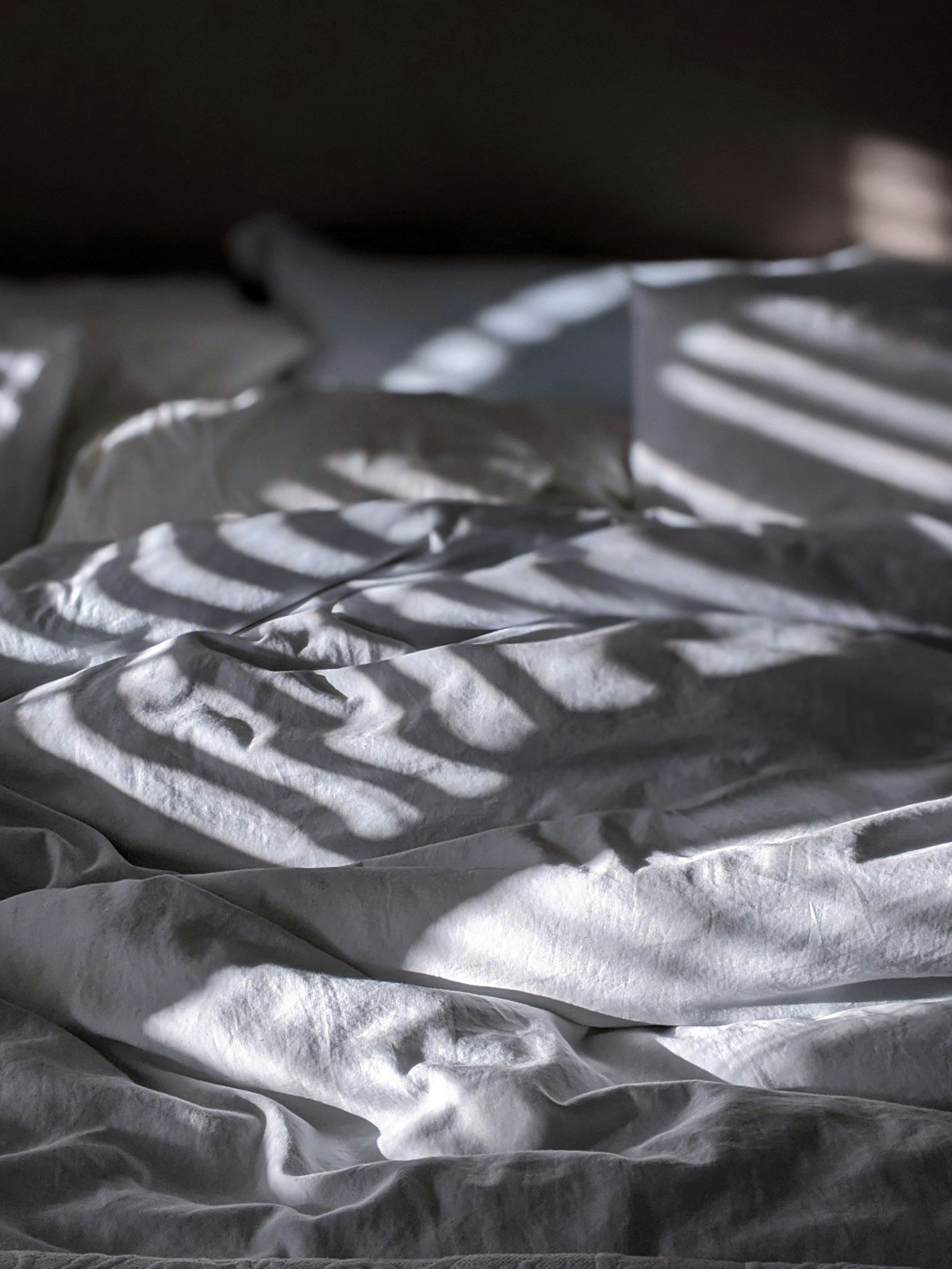 Housse de couette froissée sur un lit défait, illustrant la corvée quotidienne du linge de lit